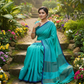 Turquoise mulmul cotton saree sitting in garden
